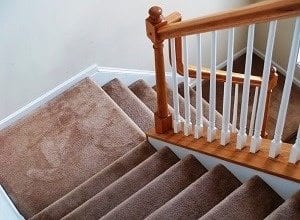 Wooden stairwell with beige wall-to-wall carpeting